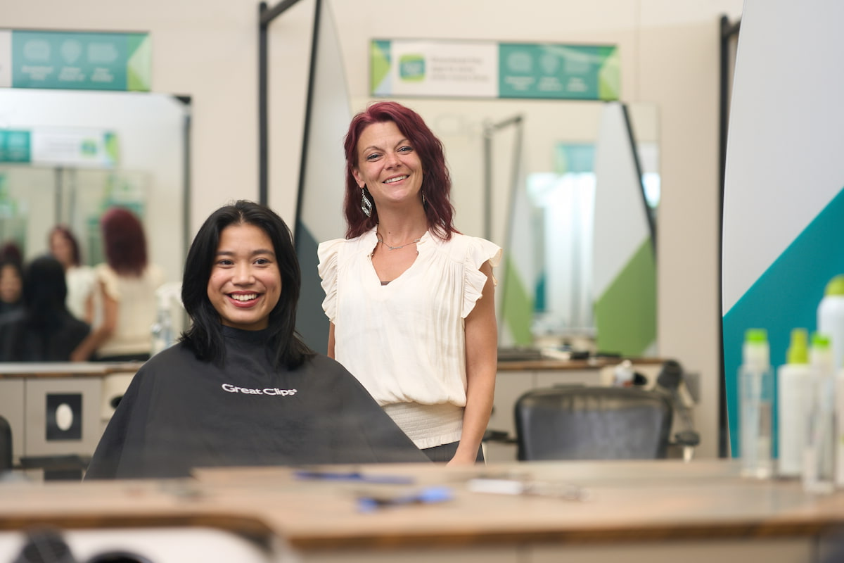 A woman smiling in a Great Clips salon chair next to her stylist